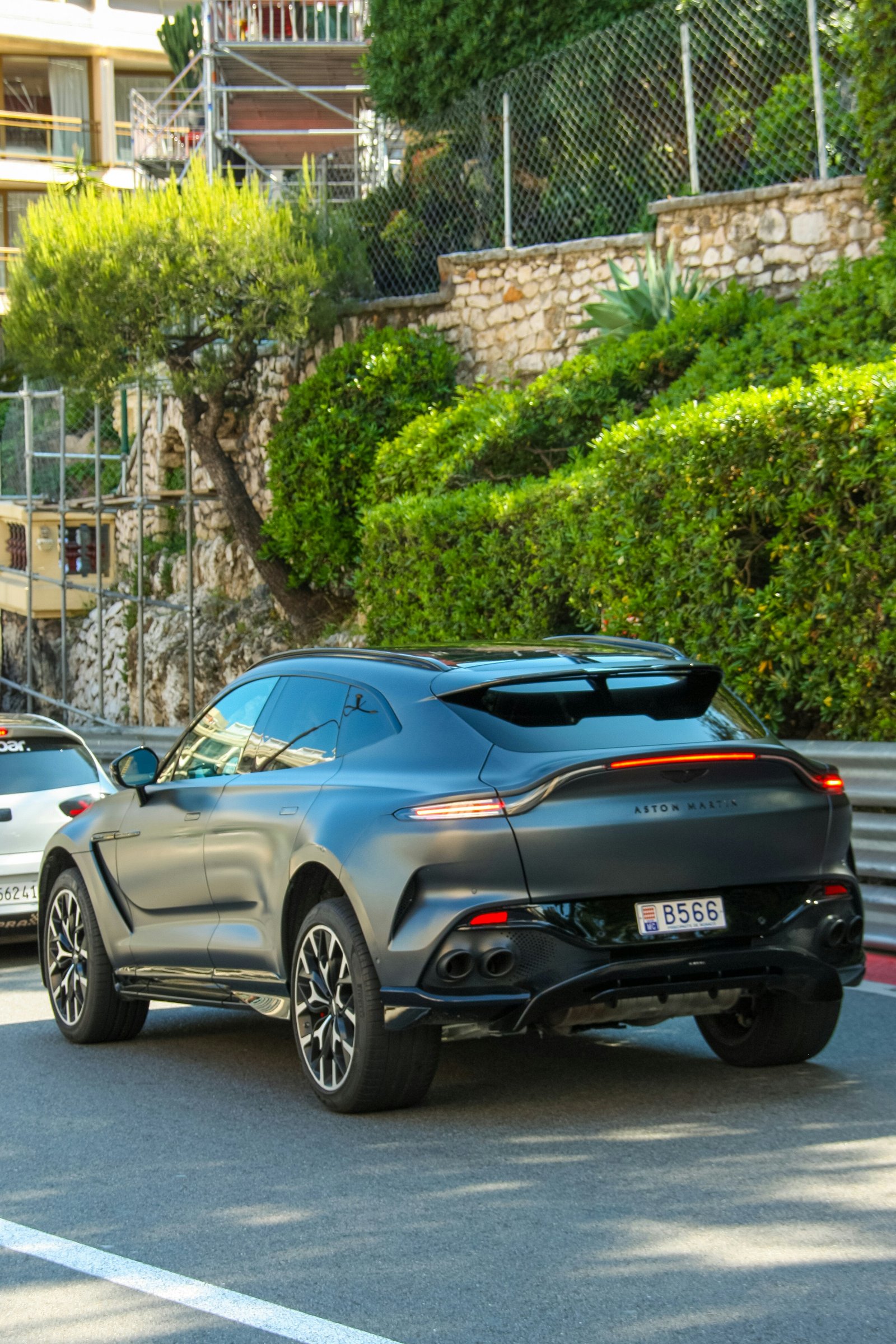 Aston Martin DBX in satin dark grey, rear three-quarter view on a Monaco street.